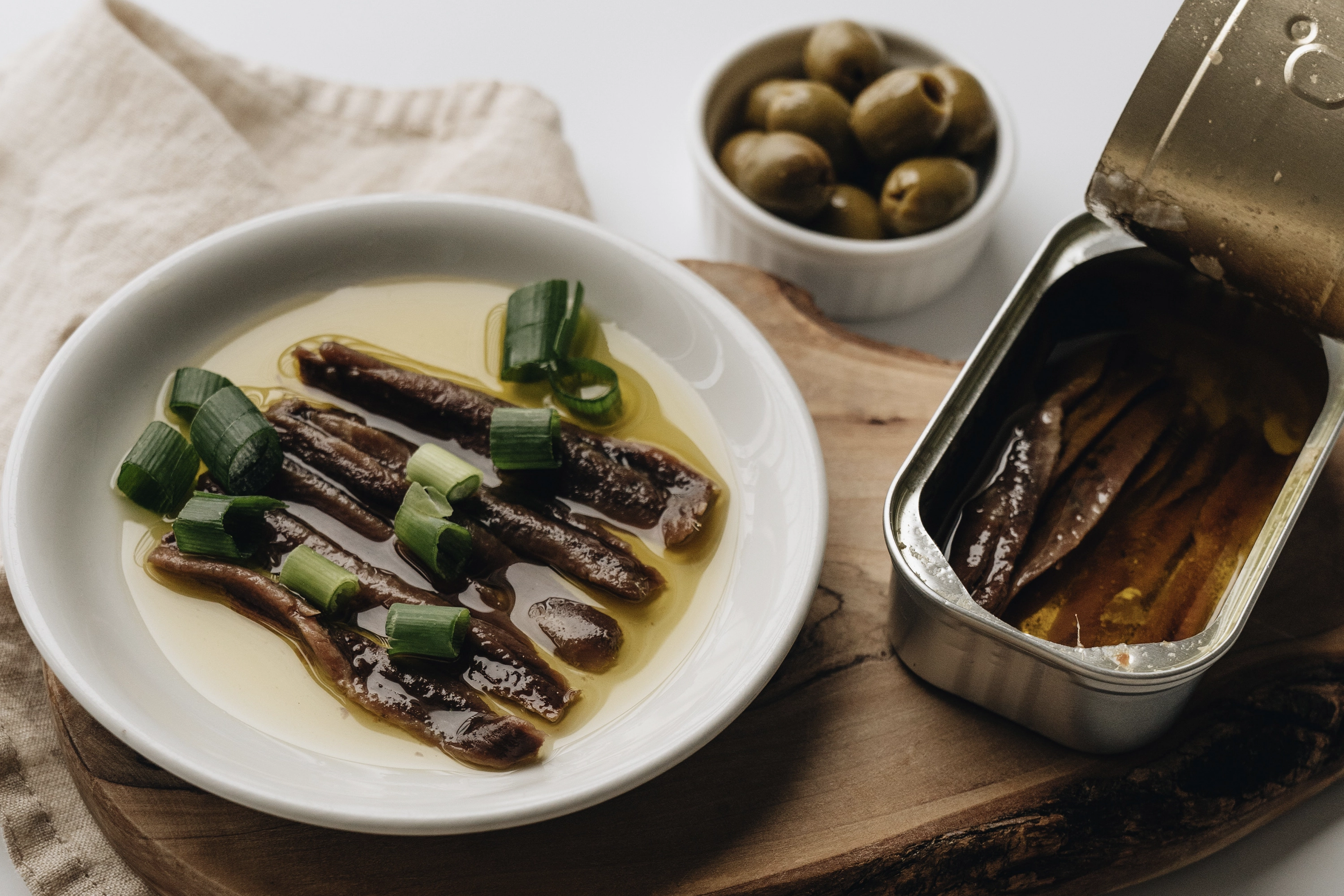 plate and tin filled with sardines and a bowl filled with olives